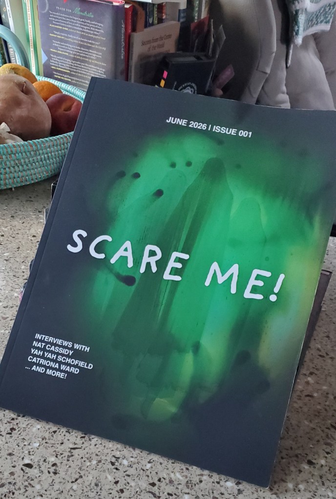 A copy of Scare Me! magazine, June 2026, Issue 001, Interviews with Nat Cassidy, Yah Yah Schofield, Catriona Ward...and more! The magazine is printed in a matte black with irredescent green hand prints and faded spirits.